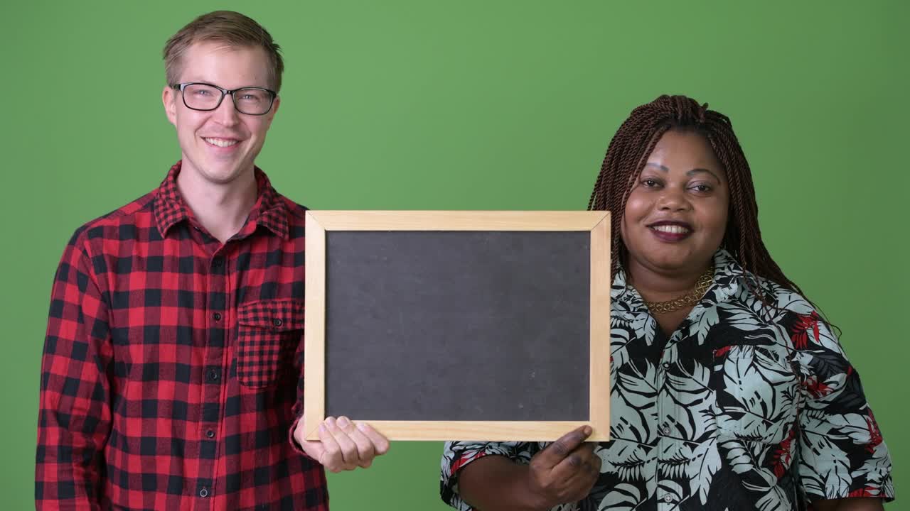 mujer africana con sobrepeso y un joven escandinavo juntos contra un fondo verde