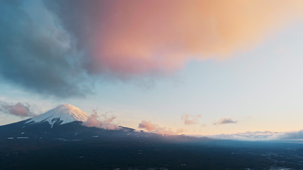 Aerial drone view of Mount Fuji with snow at the top and clouds moving around in daylight