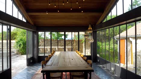 Modernized-long-table-dining-hall-at-French-Villa-with-artistic-bulb-hanging-chandelier-above,-Pedestal-down-reveal-shot