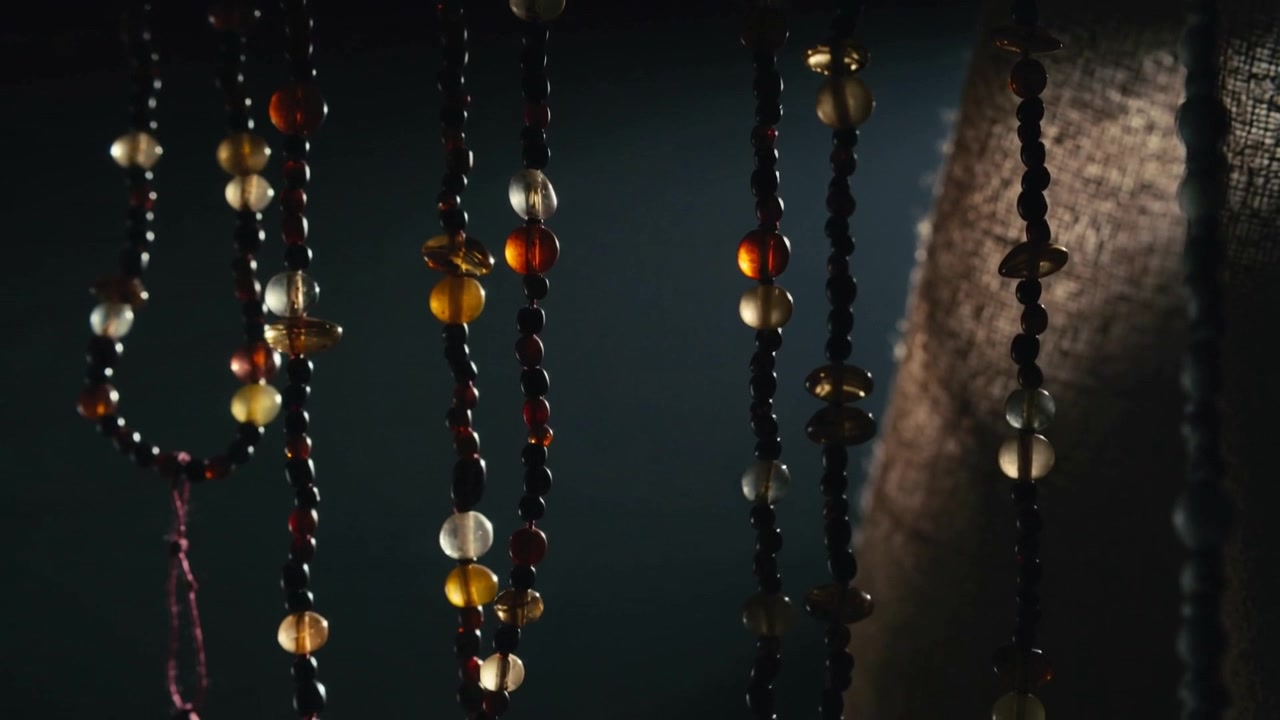 Grazing side light causing beads swaying, turning in dim room, knotted loop, woven fabric showing
