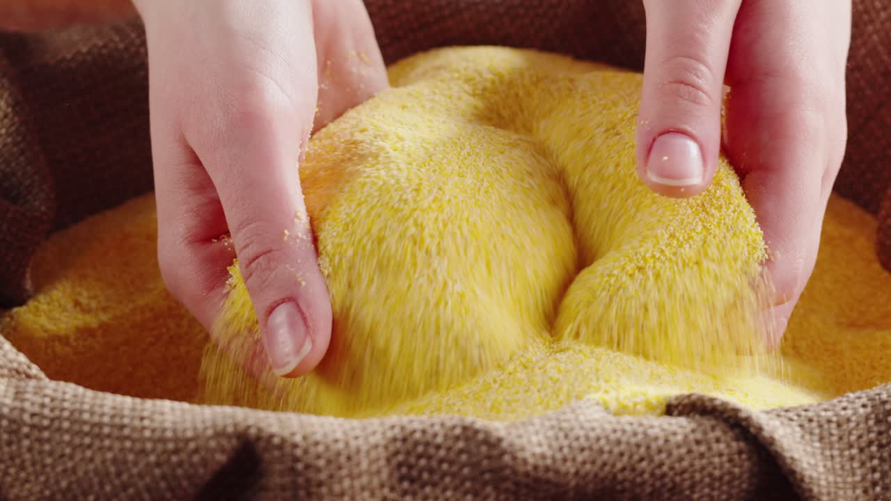 Hands Pouring and Sifting Cornmeal in a Sack
