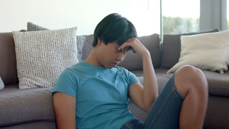 Teenage-Asian-boy-looks-stressed-sitting-on-a-couch-at-home