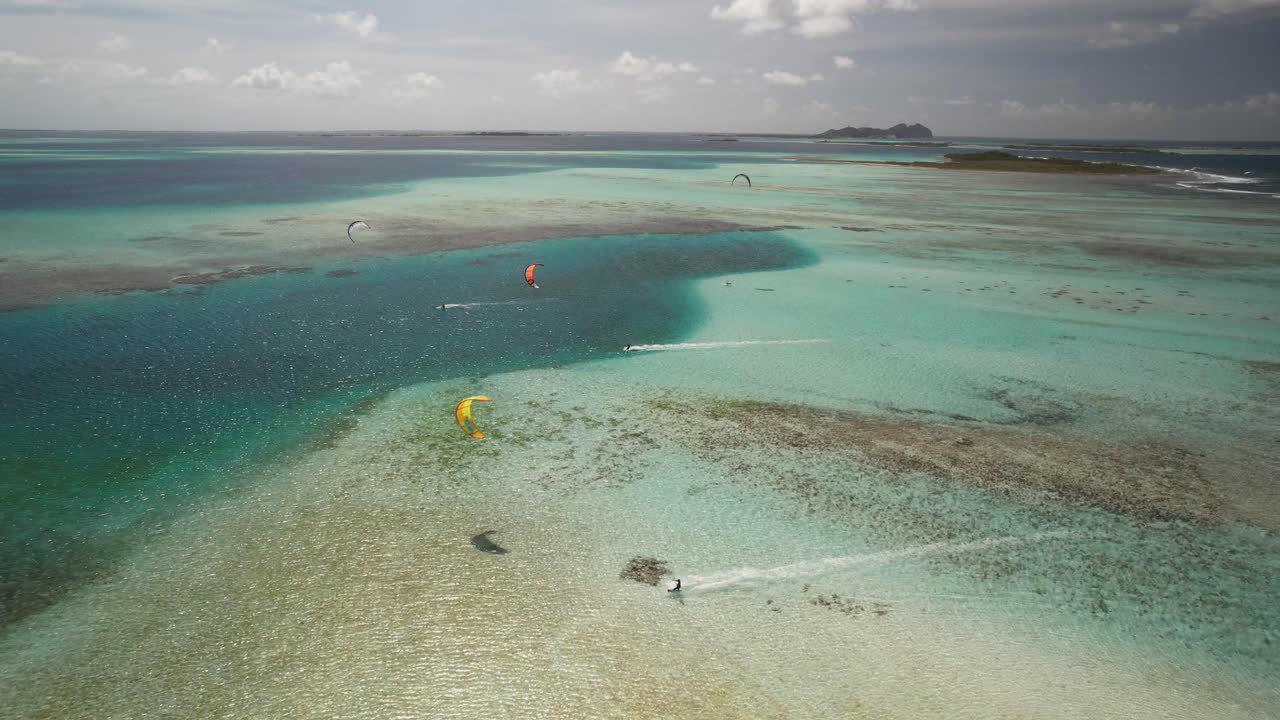 kite surfers deslizándose sobre las aguas claras de color turquesa en cayo de agua, los rocas, vista aérea