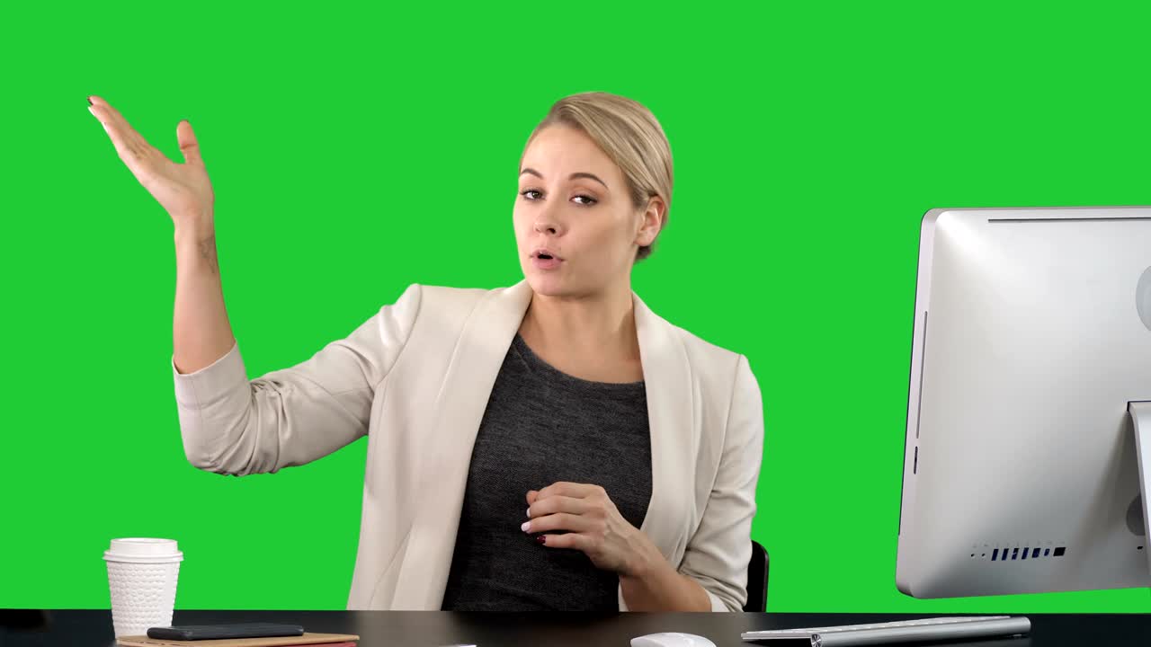 Lady looking and talking to camera at her work desk and pointing to the sides on a Green Screen, Chroma Key