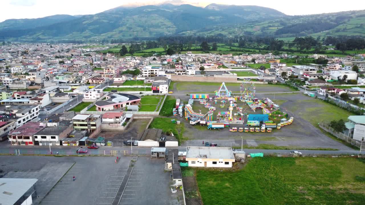 clip de un dron volando lateralmente sobre un parque de atracciones con una gran rueda de ferris cerca de una aldea en machchi, ecuador