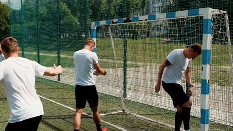 male soccer team playing and scoring a goal on a street football pitch on a sunny morning