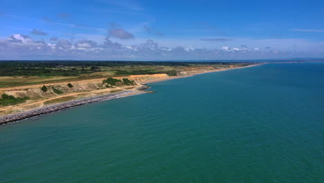 Aerial-flying-over-sea-towards-coastline-with-beach-and-cliffs-sunny-day-UK-4K