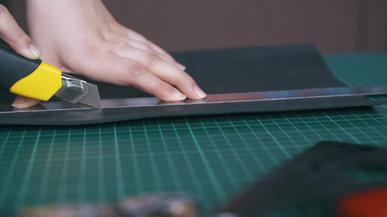 조심스러운  ⁇ 은 상자 절단기로 검은 가죽 옷을 잘라