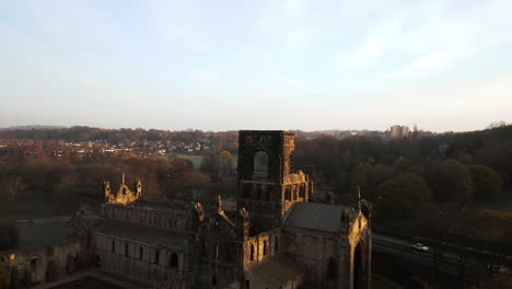 aerial tracking shot of kirkstall abbey at dawn on sunny spring day side on with sun