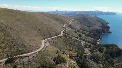 road cuts across terraced hillside above lake titicaca in bolivia