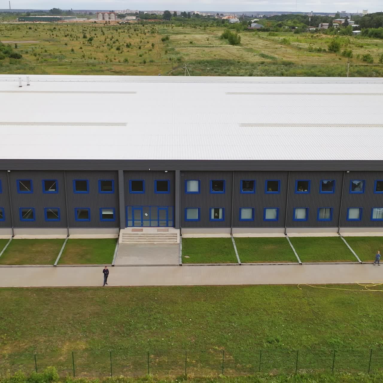 Facade of a modern two-storey building. Industrial plant outdoors. Aerial panorama of beautiful manufacturing with car parking. Summer time.