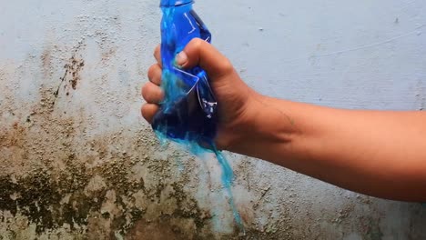 apretar a mano la botella llena de líquido azul
