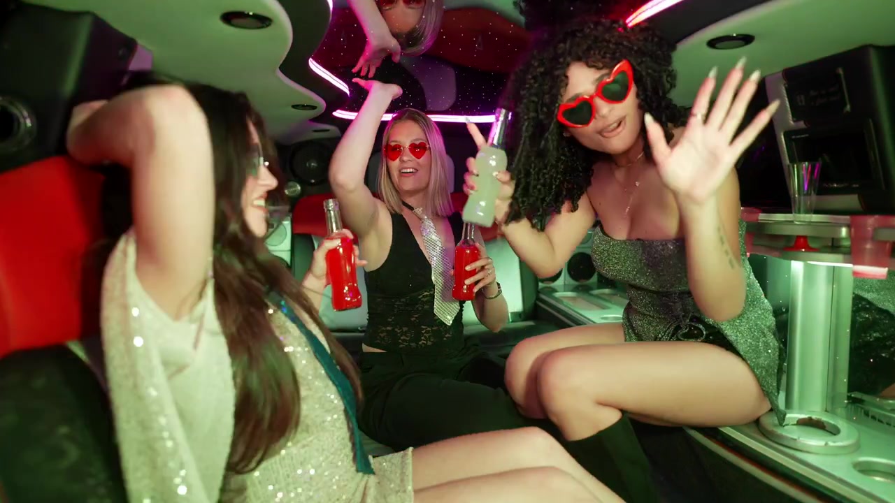 Donne felici che ballano e bevono in una limousine da festa