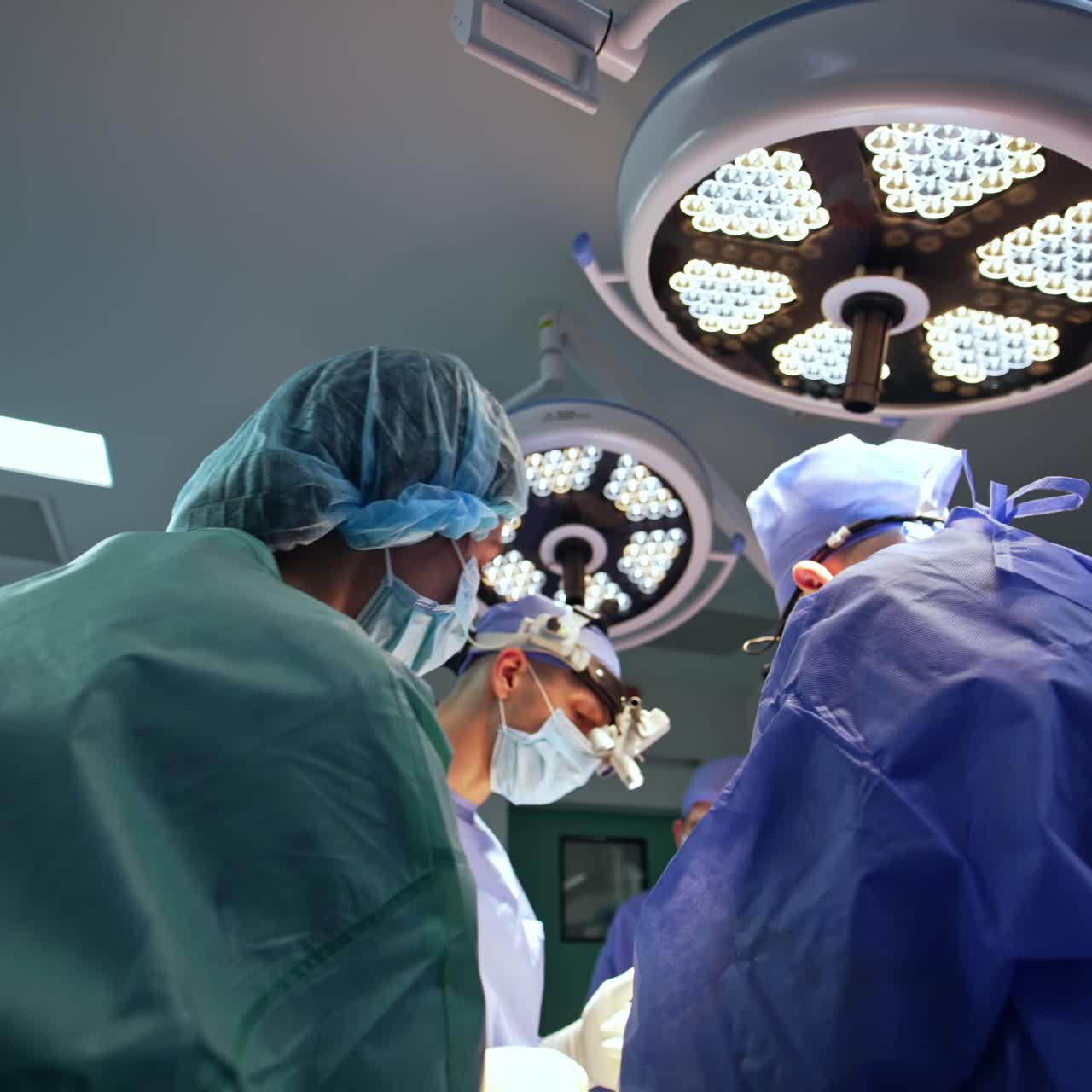 Surgeon's team performing operation. Main neurosurgeons wear device glasses. Low angle view