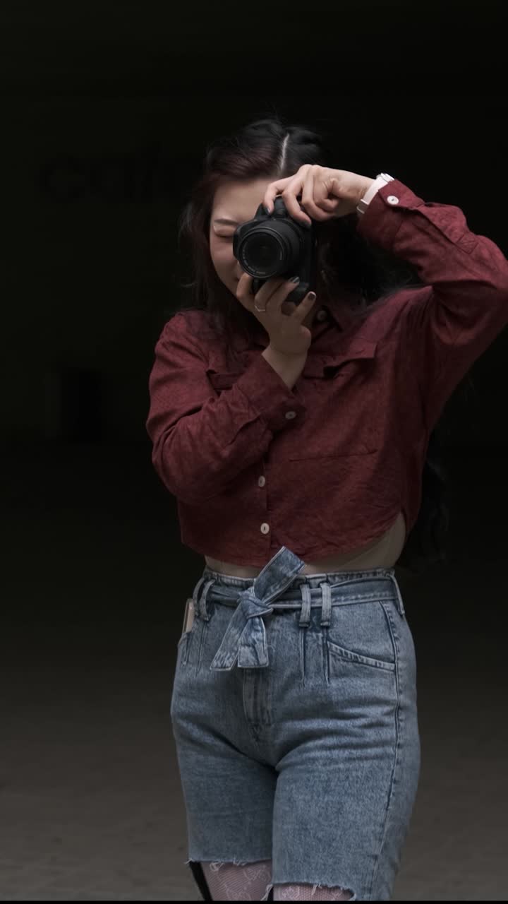 Young asian woman photographer taking a photo with a professional camera to someone