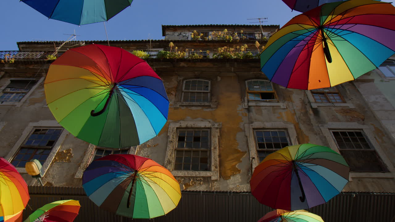 paraguas de arco iris coloridos colgando sobre la calle rosa en lisboa, portugal