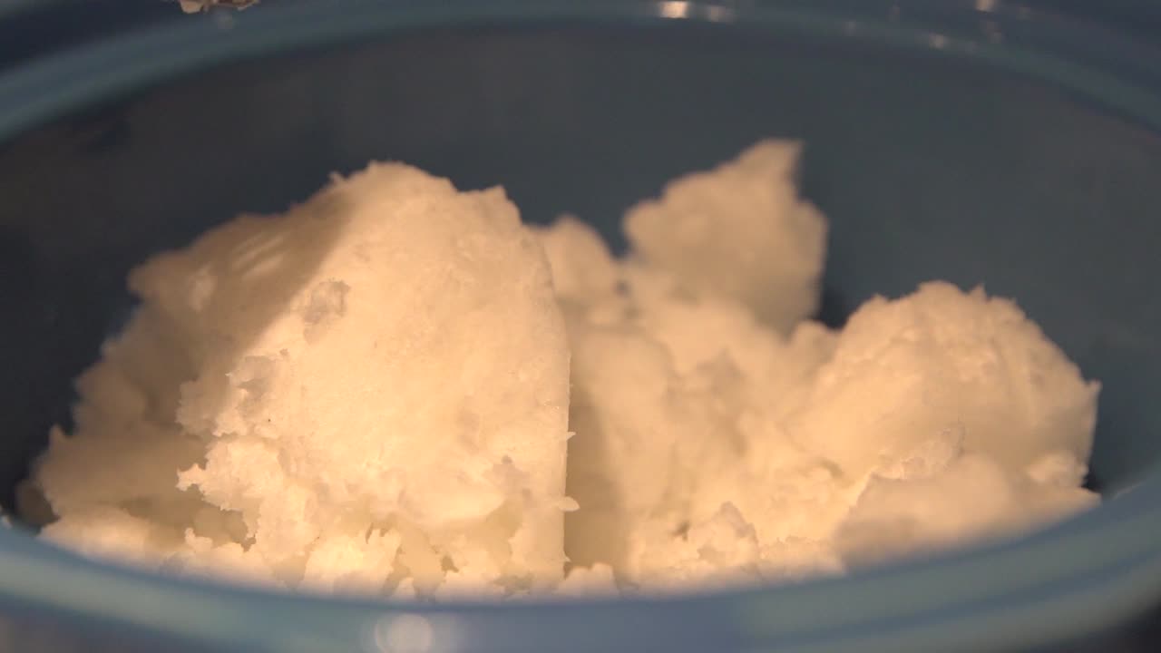 Shea butter being added for cannabis salve oil preparation, close up