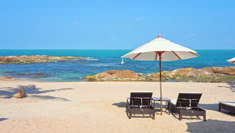 Sun-umbrella-and-deckchair-on-white-empty-beach-with-sea-in-background