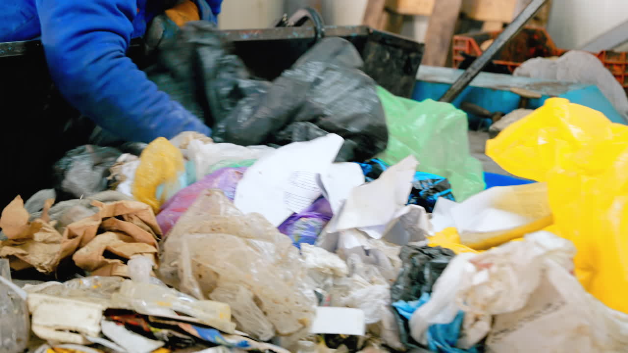 Employee working with garbage moving on a conveyor belt at waste sorting plant