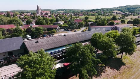 Aerial-view-of-Martel-and-the-train-station-with-travellers-and-tourists-in-summer,-Lot,-France