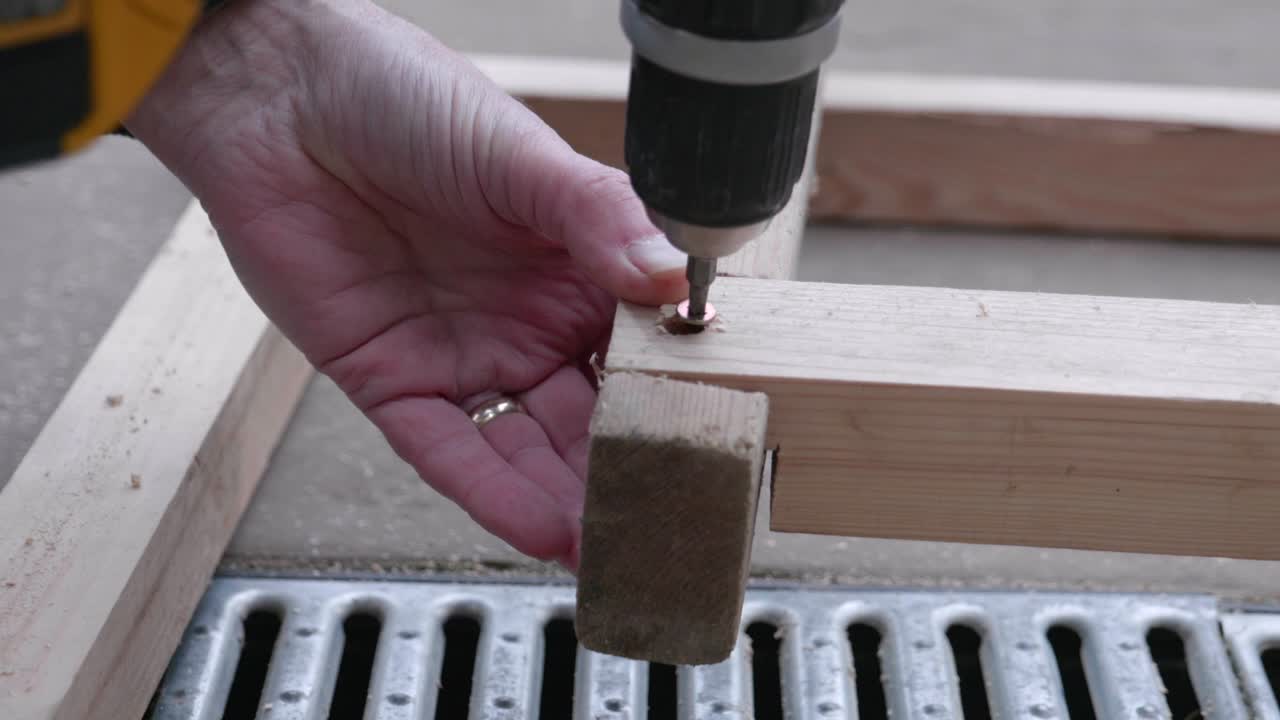 A man holding a wood frame and screwing together.