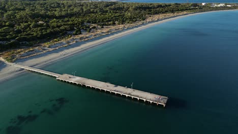 Toma-Aérea-De-Arriba-Hacia-Abajo-Del-Embarcadero-En-La-Playa-De-Woodman-Point-Rodeada-De-Agua-Clara-Del-Océano-Al-Amanecer