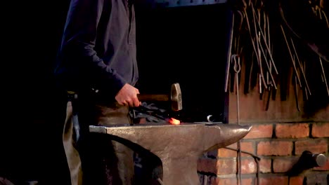 a blacksmith hammers metal on an anvil in a dimly lit workshop, showcasing traditional craftsmanship in ballarat, victoria