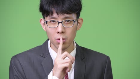 입술에 손가락을 은 젊은 아시아 사업가