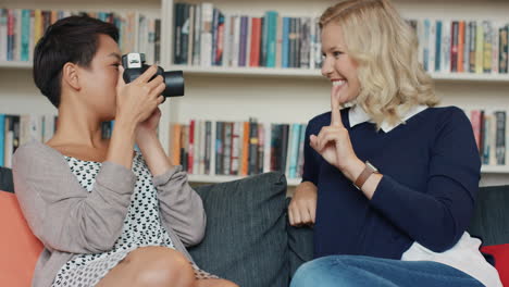 Girl-friends-having-fun-hanging-out-at-home-using-instant-camera-taking-photos