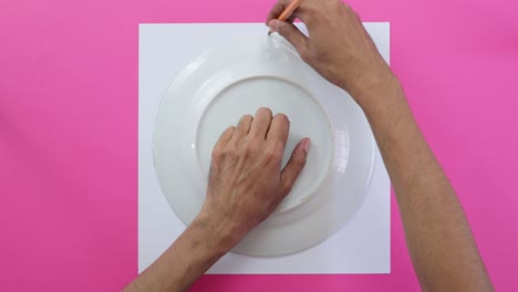 using porcelain plate to draw circumference on paper, pink background
