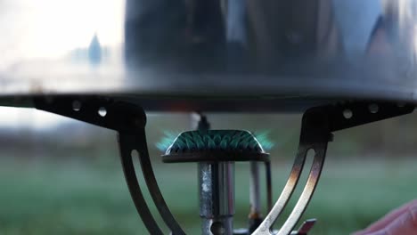 olla de hierro sobre la estufa de gas - la persona aumenta el fuego en la estufa para cocinar inmediatamente