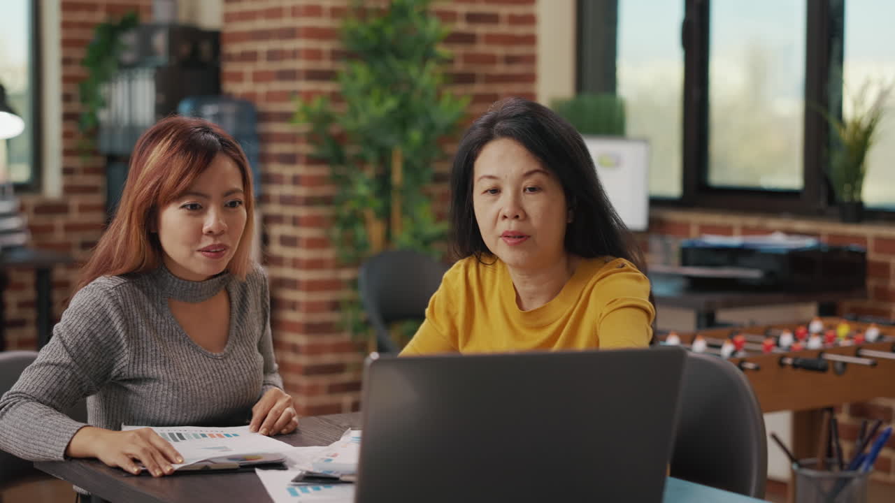 Asian women looking at laptop screen to research finance