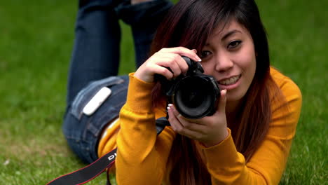 una chica asiática bonita tomando una foto en el césped