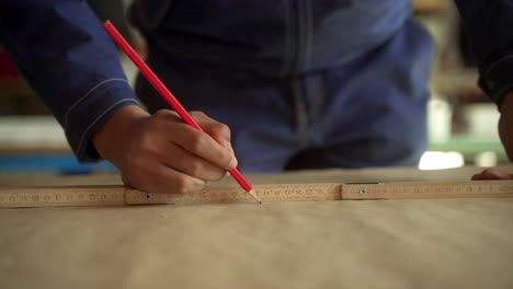 expert artisan taking measurement with ruler and red lead pencil