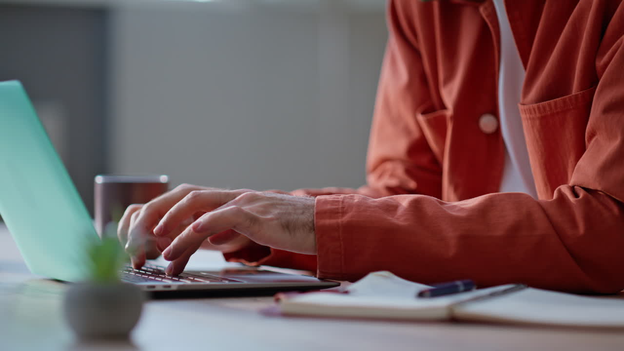 Lachende start-up ondernemer die mobiel belt en op een laptop werkt op de werkplek van dichtbij