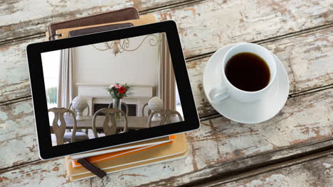 tableta digital con interiores modernos de comedor mostrados en la pantalla en una superficie de madera