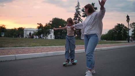 mother and daughter skateboarding at sunset