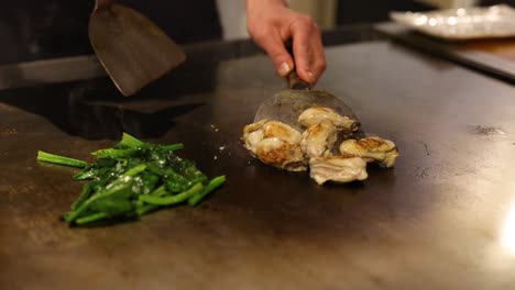 chef prepares oysters and greens on hot grill