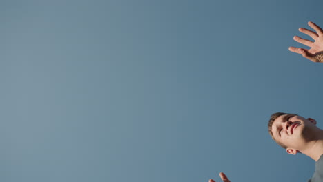 vista hacia arriba de un hombre preparándose para servir voleibol bajo un cielo brillante y despejado, centrarse en las manos y la pelota, enfatizando la acción de voleibol en un entorno al aire libre con tiempo soleado