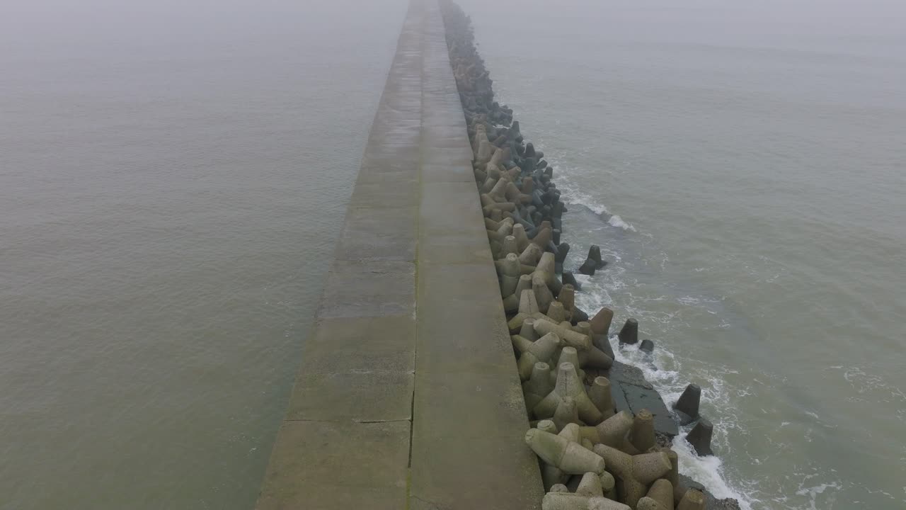 리파자 콘크리트 부두 항구, 발트해 해안선, 짙은 안개가 낀 안개 낀 날, 변덕스러운 느낌, 큰 폭풍우가 튀는 것, 넓은 버드아이 드론 샷이 앞으로 움직이는 모습