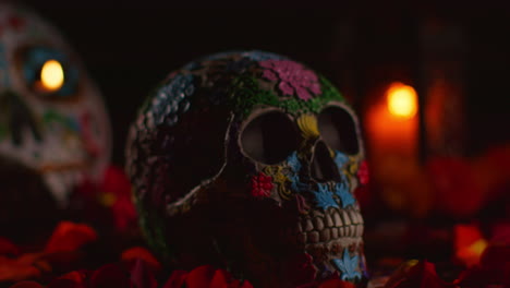 still life of decorated skull surrounded by candles and flower petals celebrating mexican holiday of dia de muertos or day of the dead