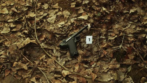 Crime-scene-investigation,-putting-marker-with-number-near-gun,-closeup-shot