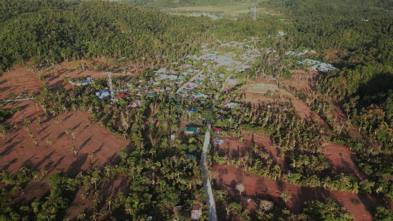 Luftoptagelse, der trækker tilbage fra Hawan Grande i Virac, Catanduanes, Filippinerne, med en landlig barangay omgivet af landbrugsjord, veje og tropisk grønt