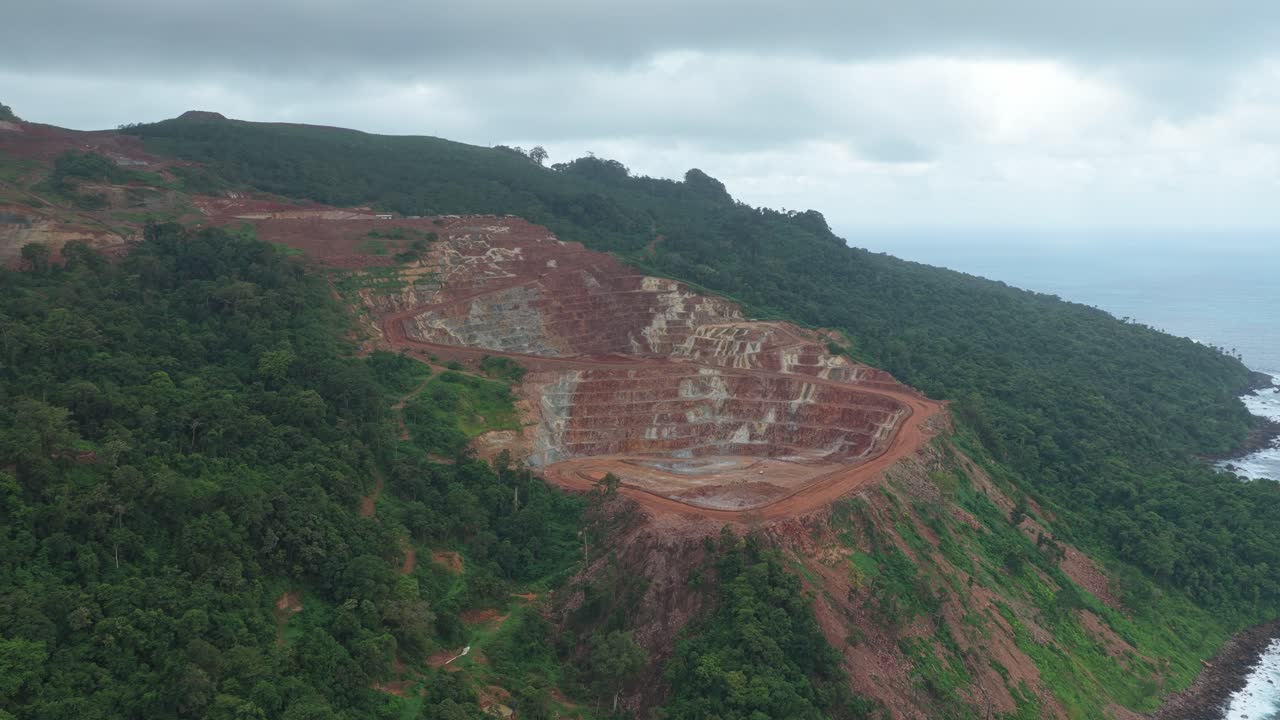 Miniera a cielo aperto che distrugge la foresta pluviale tropicale per l'estrazione di risorse.