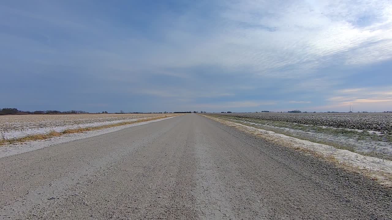 POV out of the drivers window; Driving past farms and fields in rural Illinois USA on snow and ice.