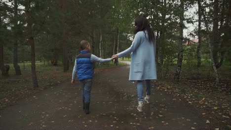 mother and son walking in the park on a rainy autumn day