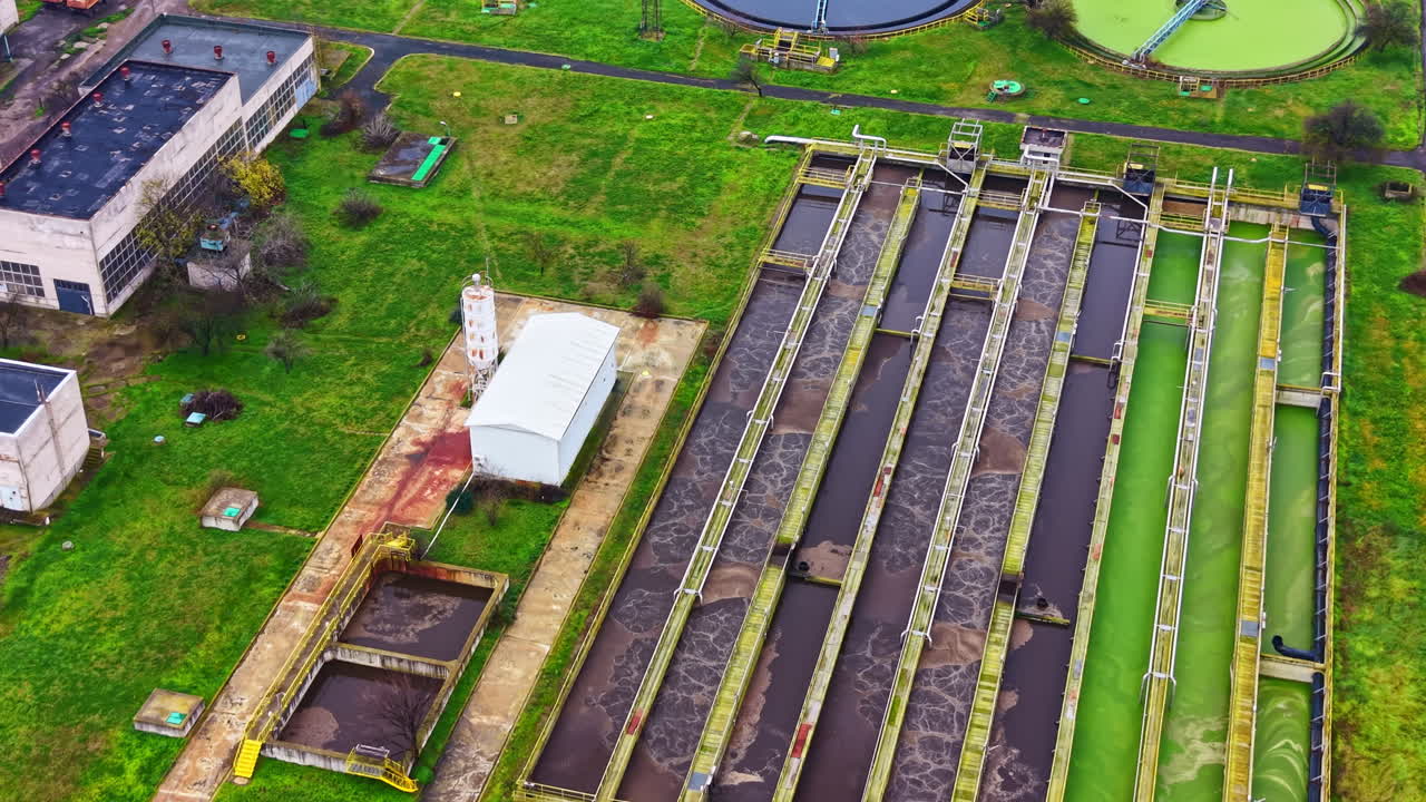 Water treatment facility operates in large green area with several processing tanks and structures engaged in waste management tasks