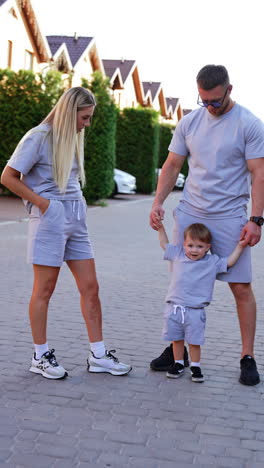 family enjoying a casual stroll outdoors. parents and their young child walk together in matching outfits on a sunny day in a residential area