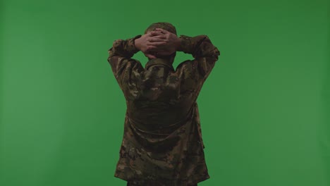 back view of distressed asian male soldier holding his head having headache while protecting his country from the war on the green screen background