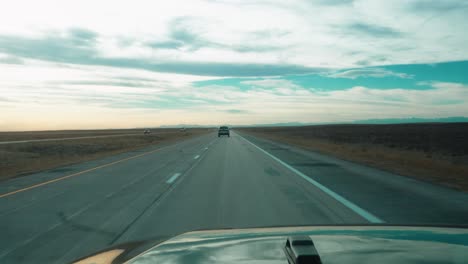 panoramic view from a car driving on open highway in flat landscape, with another vehicle in the distance